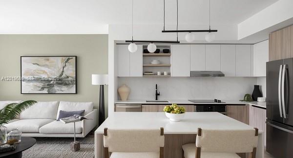A modern kitchen and living area featuring white cabinetry, a central island, and neutral furniture — 3900 Alton Road # 305, Miami Beach FL 33140, MIAMI BEACH, FL