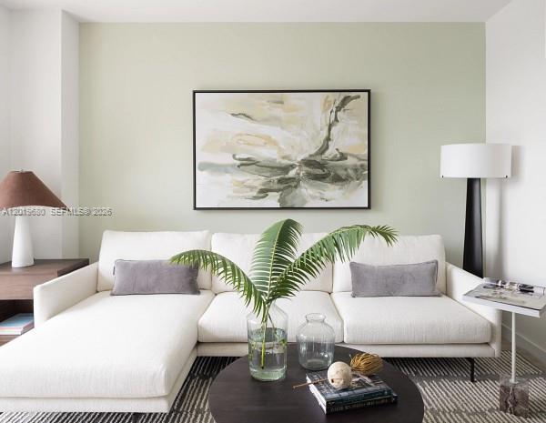 A living room features a white sectional sofa, a round coffee table, and abstract wall art — 3900 Alton Road # 305, Miami Beach FL 33140, MIAMI BEACH, FL