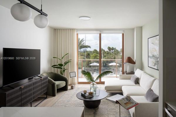 A modern living room features a white sectional sofa, a dark media console, and balcony views — 3900 Alton Road # 305, Miami Beach FL 33140, MIAMI BEACH, FL