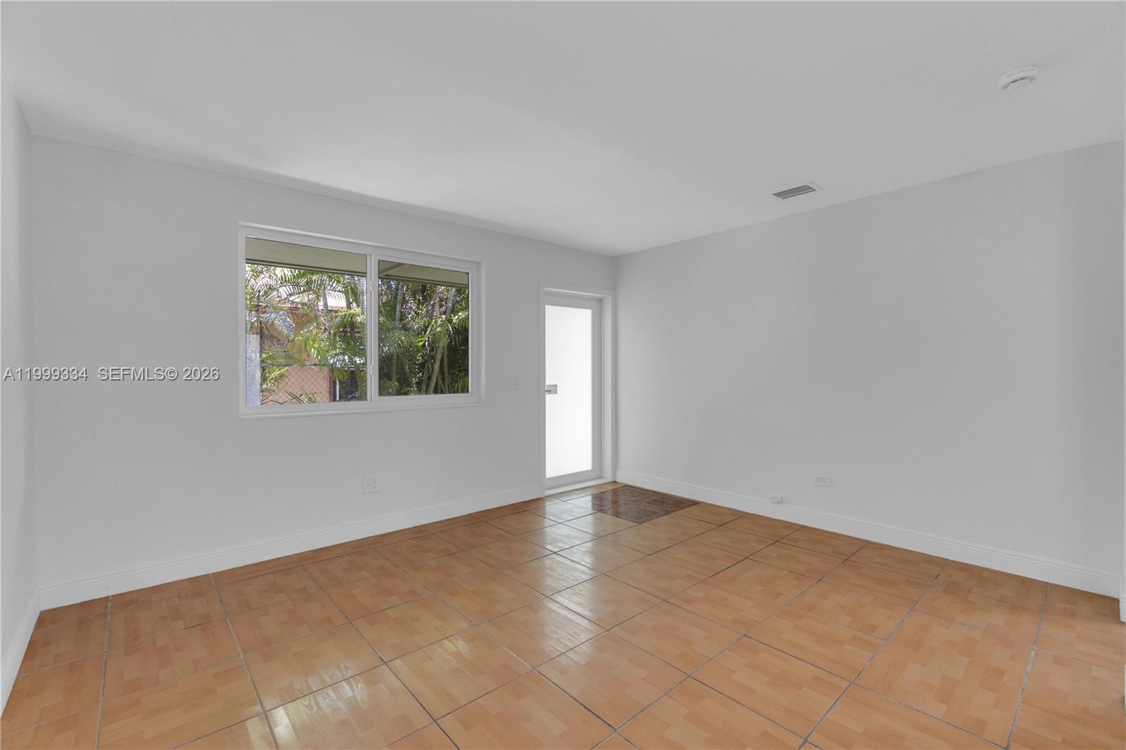 An empty room features light-colored walls, tiled flooring, a window, and a glass door — 1730 NW 55th Ter # 1730, Miami FL 33142, MIAMI, FL