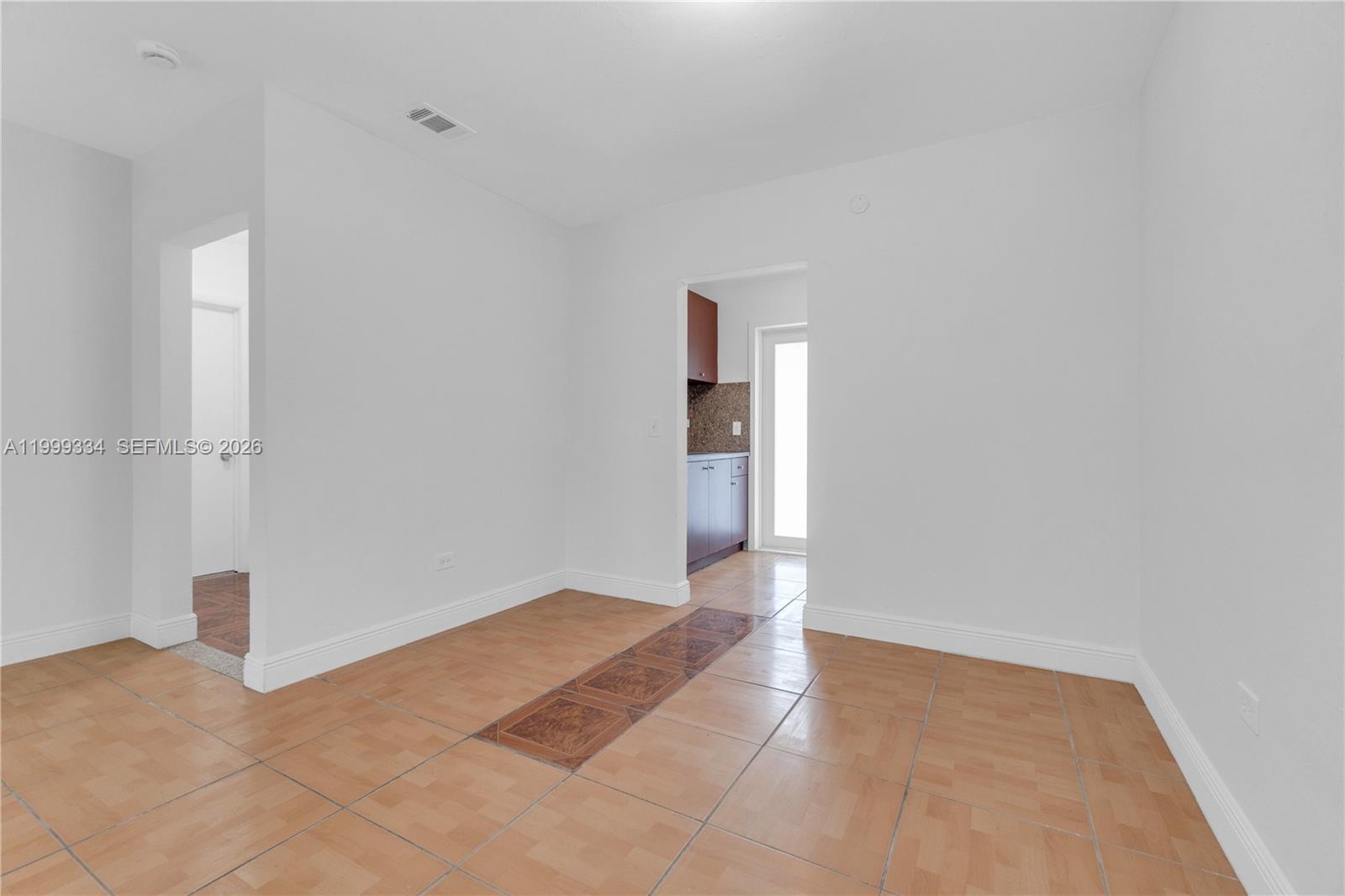 An empty room features light-colored tile flooring with a decorative central inlay and white walls — 1730 NW 55th Ter # 1730, Miami FL 33142, MIAMI, FL