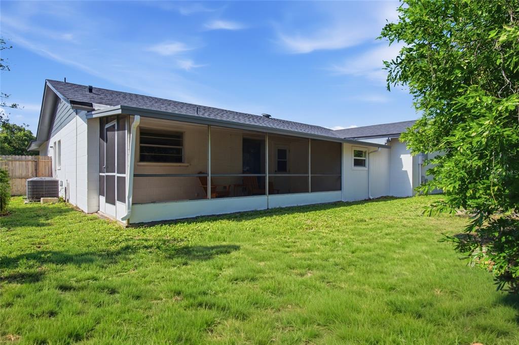 The exterior of a house features a screened-in porch and a grassy backyard — 1420 AVALON BOULEVARD, CASSELBERRY, FL