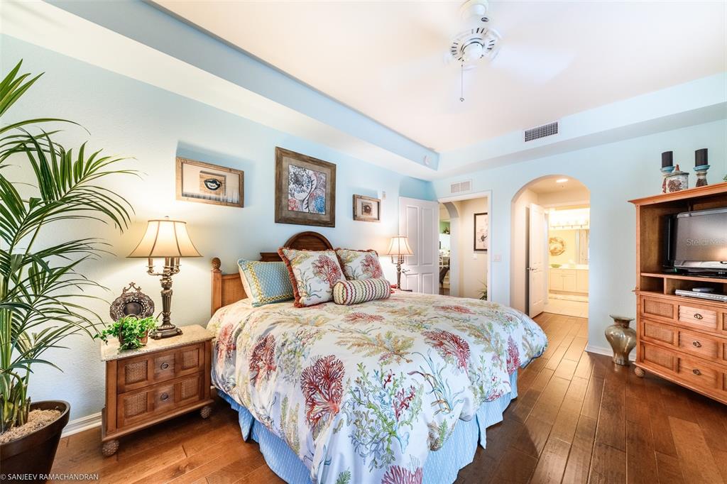 A bedroom with light blue walls, a coral-patterned bedspread, and a wooden media console — 5119 MELBOURNE STREET UNIT C-201, PORT CHARLOTTE, FL