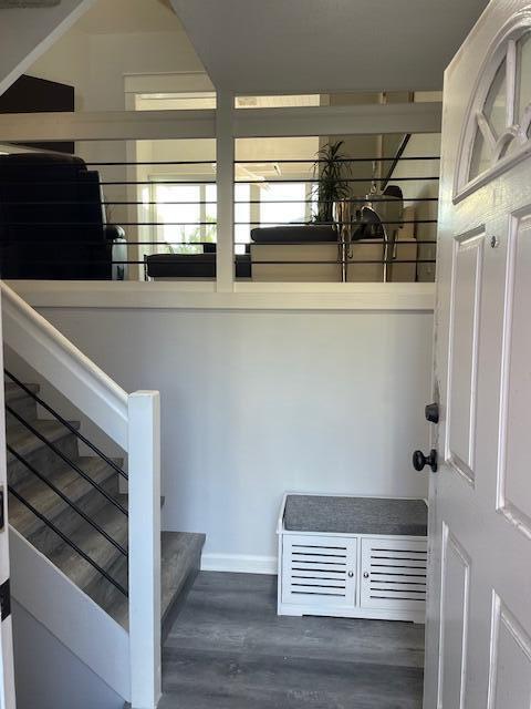 An entryway features a white storage bench, grey wood-look flooring, and stairs with metal railings — 3602 Fairway Drive N, Jupiter FL 33477, JUPITER, FL