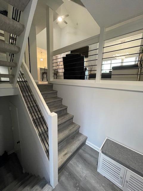 A staircase with wood-look steps and a black metal railing leads to an upper landing — 3602 Fairway Drive N, Jupiter FL 33477, JUPITER, FL
