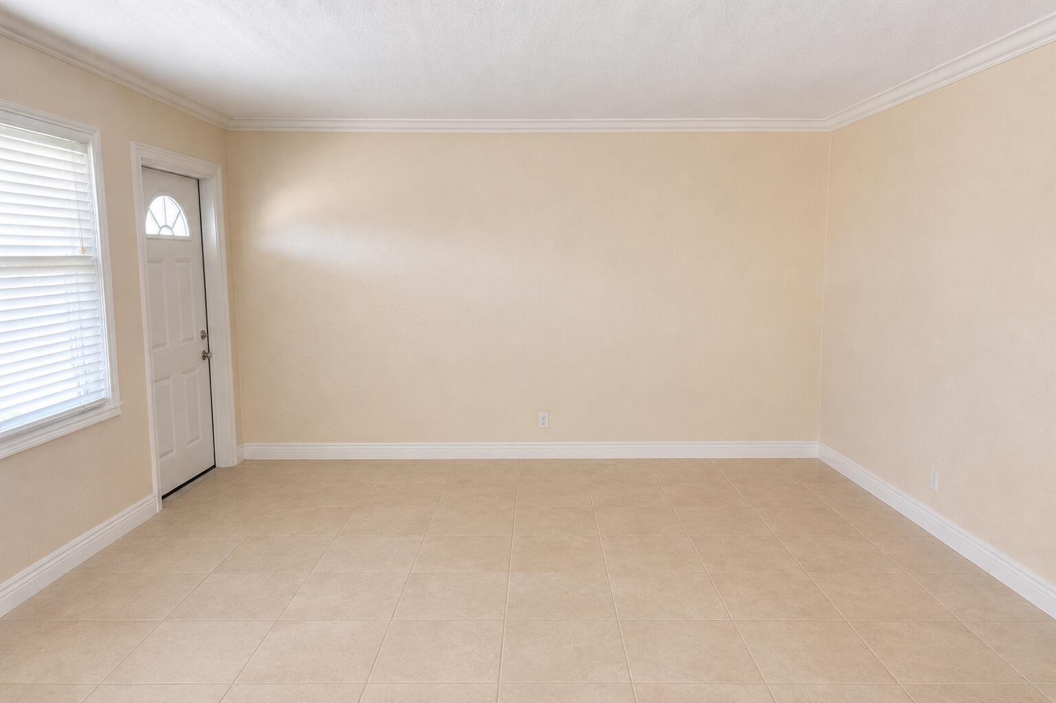 An empty room with beige walls, tile flooring, a window with blinds, and a white door — 1221 SE 3rd Street # 4, Deerfield Beach FL 33441, DEERFIELD BEACH, FL