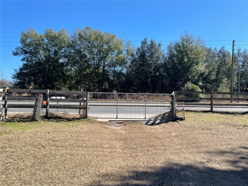 A metal gate provides access to a road through a wooden fence on a lot — 4456 NW 44TH AVENUE, OCALA, FL