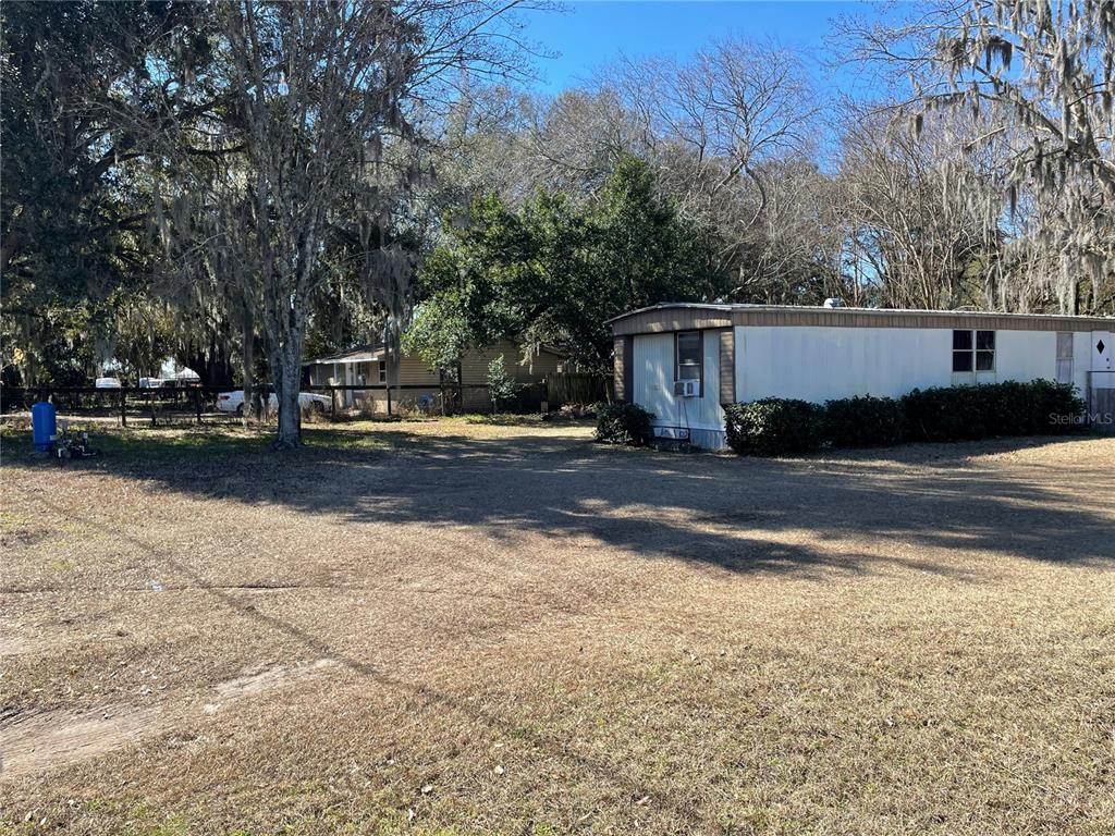 A mobile home sits on a large, grassy lot surrounded by mature trees — 4456 NW 44TH AVENUE, OCALA, FL