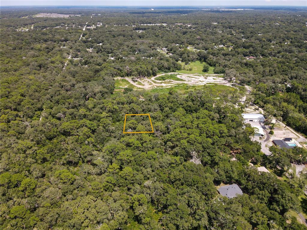 An aerial view shows a rectangular plot of land outlined in yellow amidst dense forest — BOSTON (PAPER) AVENUE, ORANGE CITY, FL