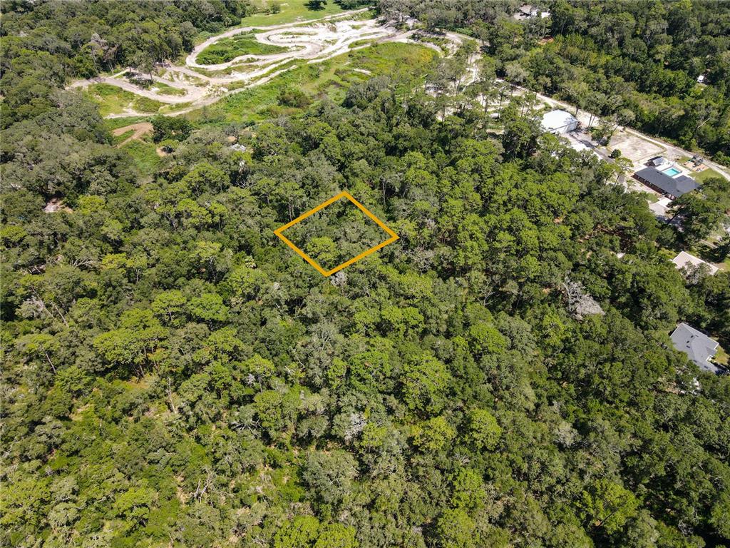 An aerial view shows a rectangular plot of land highlighted in yellow amidst dense forest — BOSTON (PAPER) AVENUE, ORANGE CITY, FL