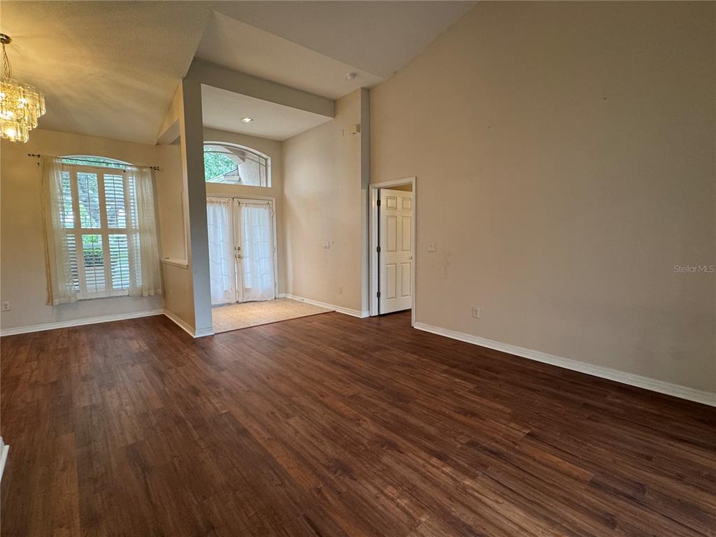 A living room with wood-look flooring, high ceilings, a chandelier, and a glass-paned entryway — 10207 QUAILS LANDING AVENUE, TAMPA, FL