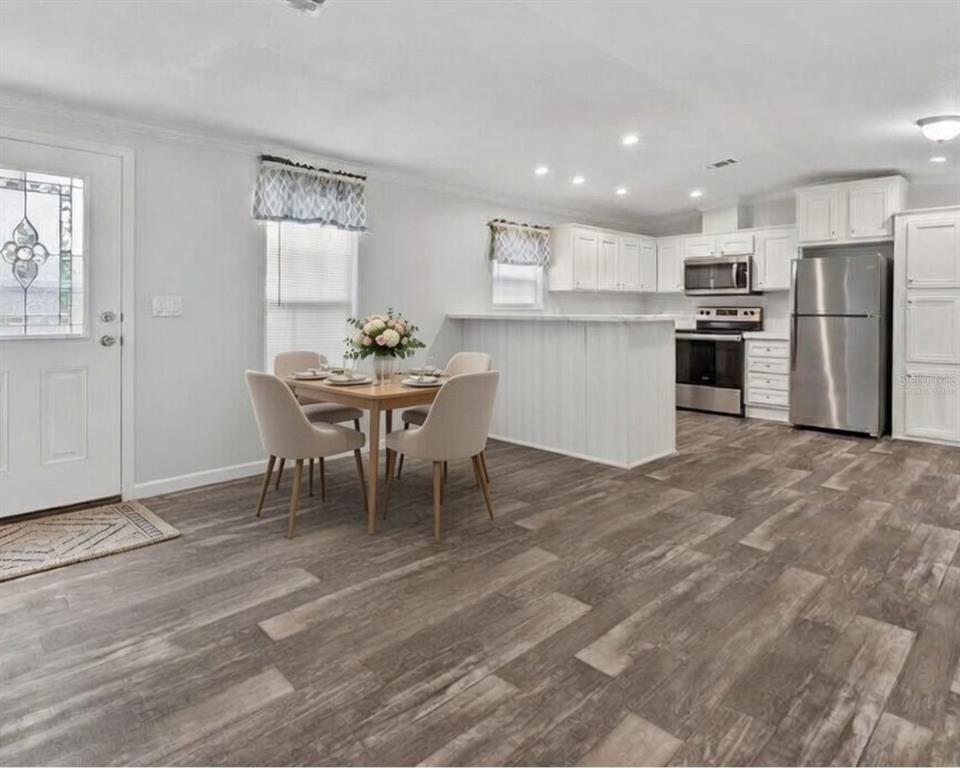 A dining area with a table and chairs sits adjacent to a white kitchen — 3035 CRYSTAL HILLS DRIVE, LAKELAND, FL