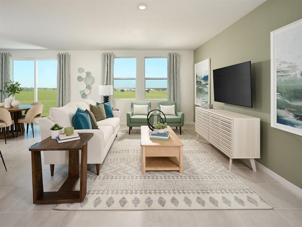 A living room features a white sofa, two green armchairs, and a wall-mounted television — 13718 UMBER FOREST STREET, HUDSON, FL