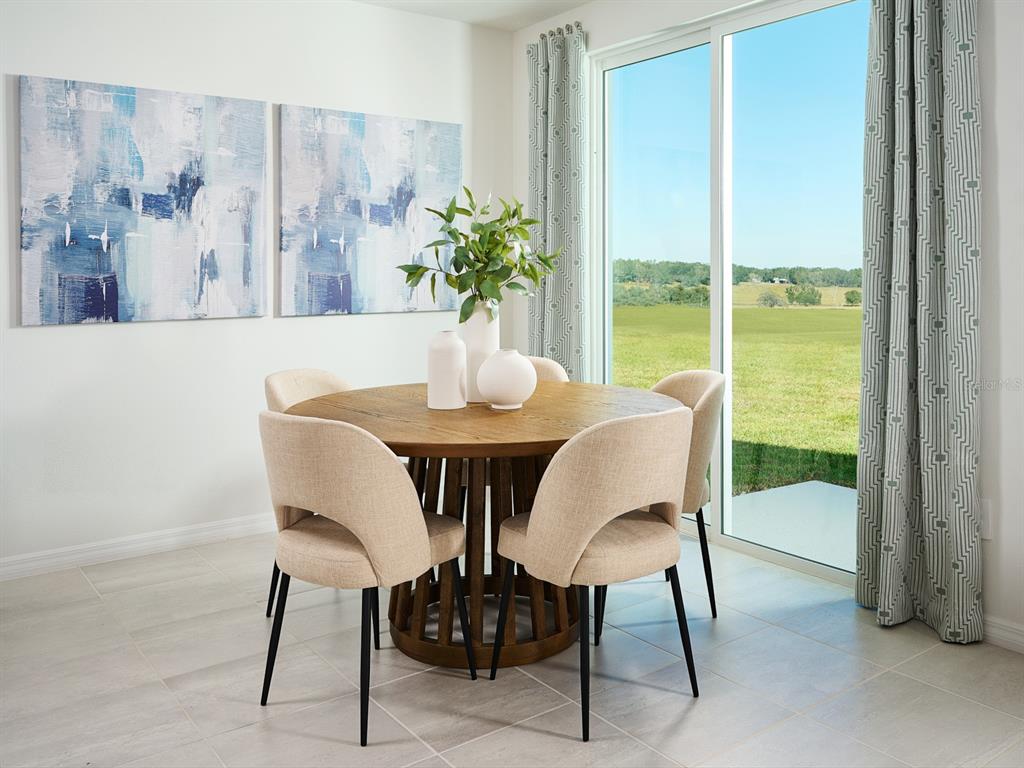 A dining area features a round wooden table with four upholstered chairs near a sliding door — 13718 UMBER FOREST STREET, HUDSON, FL