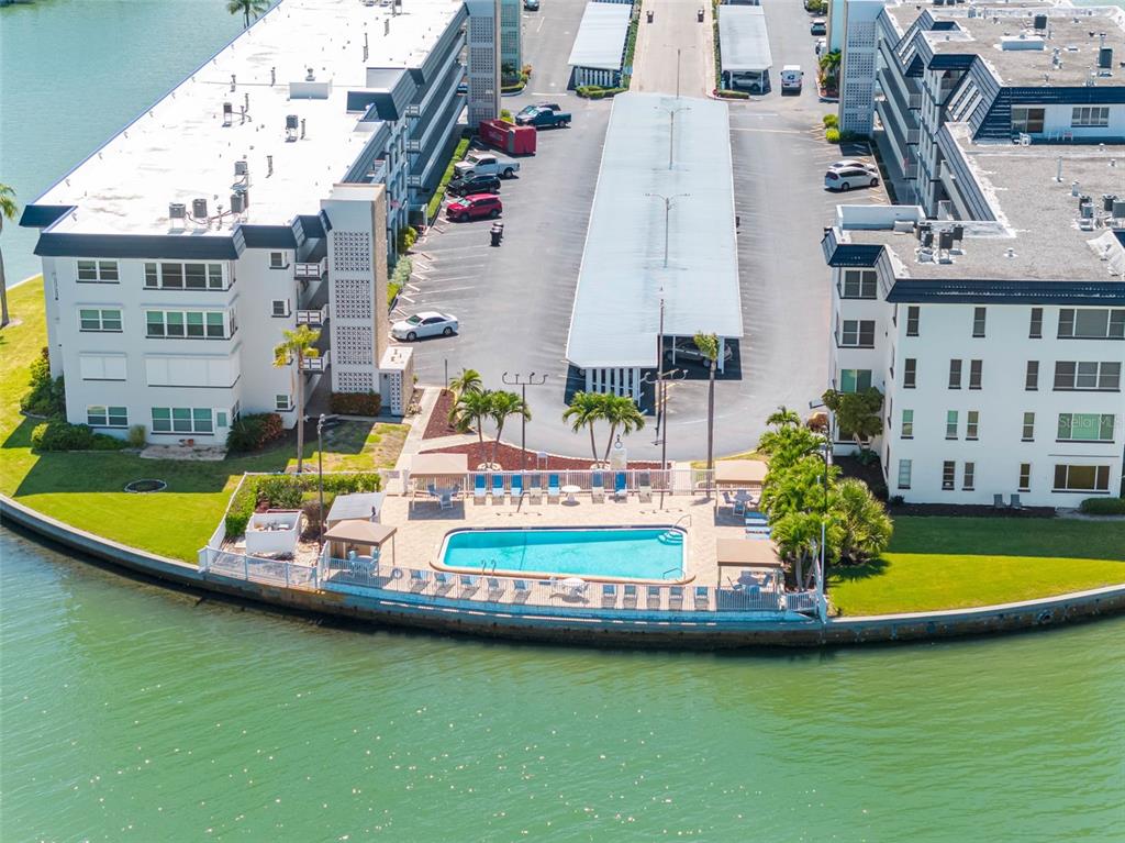 An aerial view shows a waterfront swimming pool area between two apartment buildings with parking — 5940 30TH AVENUE S UNIT 301, GULFPORT, FL