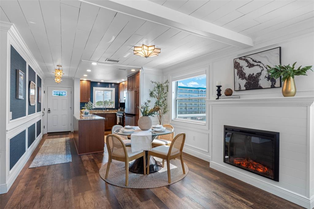 A dining area with a glass table, fireplace, and kitchen visible in an open floor plan — 5940 30TH AVENUE S UNIT 301, GULFPORT, FL