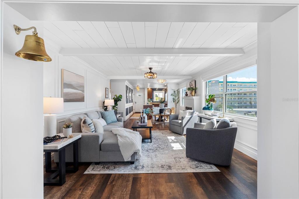 A bright living room features white shiplap ceilings, dark wood floors, and a large sectional sofa — 5940 30TH AVENUE S UNIT 301, GULFPORT, FL