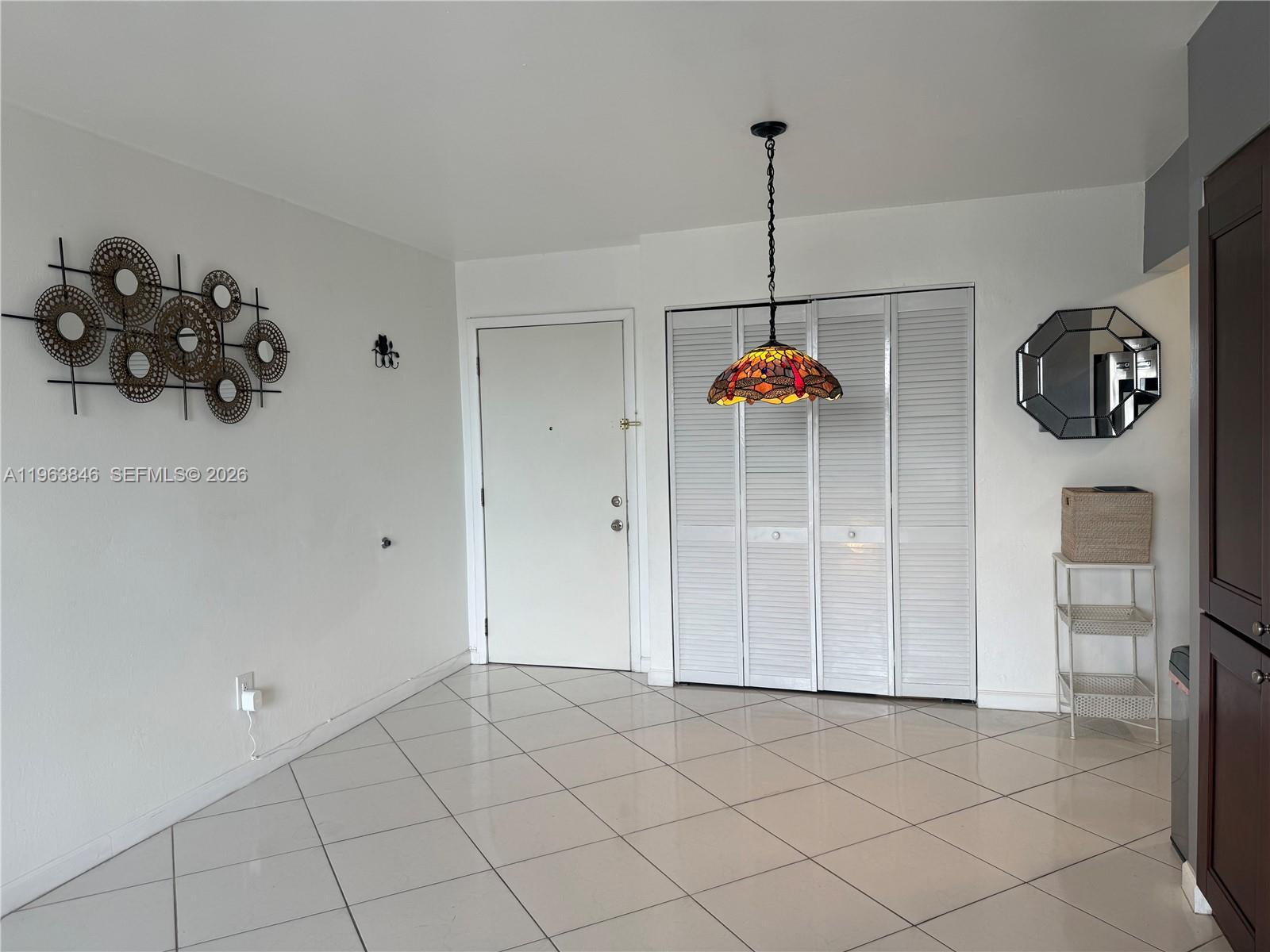 A room with white walls, tiled floors, a stained-glass pendant light, and a closet — 8821 W Flagler St # 411, Miami FL 33174, MIAMI, FL