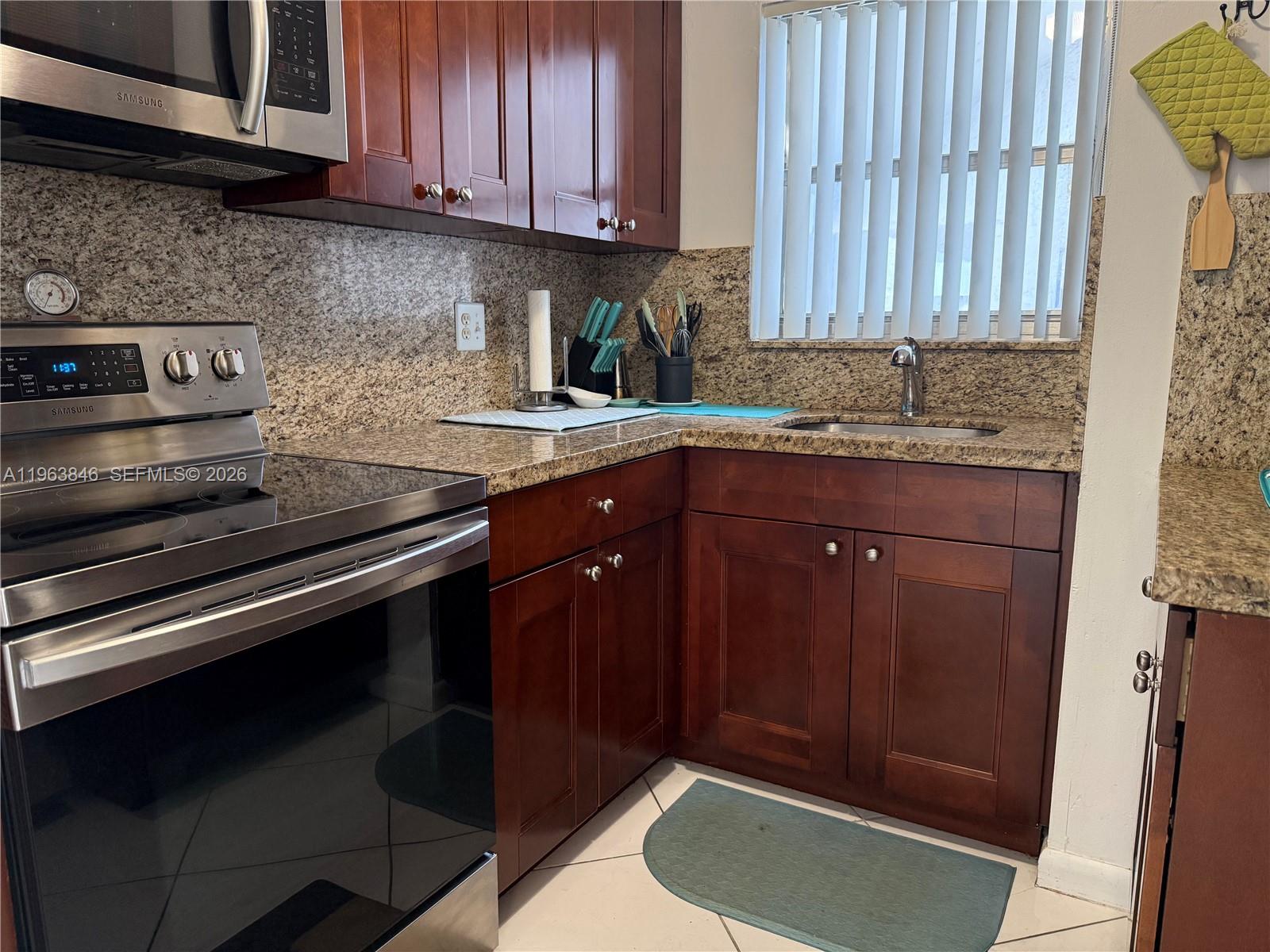 A kitchen features dark wood cabinets, granite countertops, and stainless steel appliances — 8821 W Flagler St # 411, Miami FL 33174, MIAMI, FL