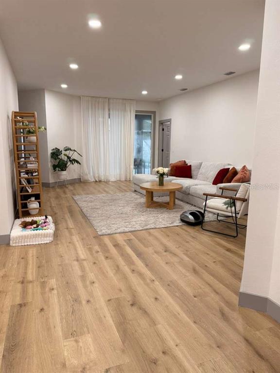 A living room features light wood flooring, a sectional sofa, and a wooden coffee table — 15020 LAKE AZURE DRIVE, ORLANDO, FL