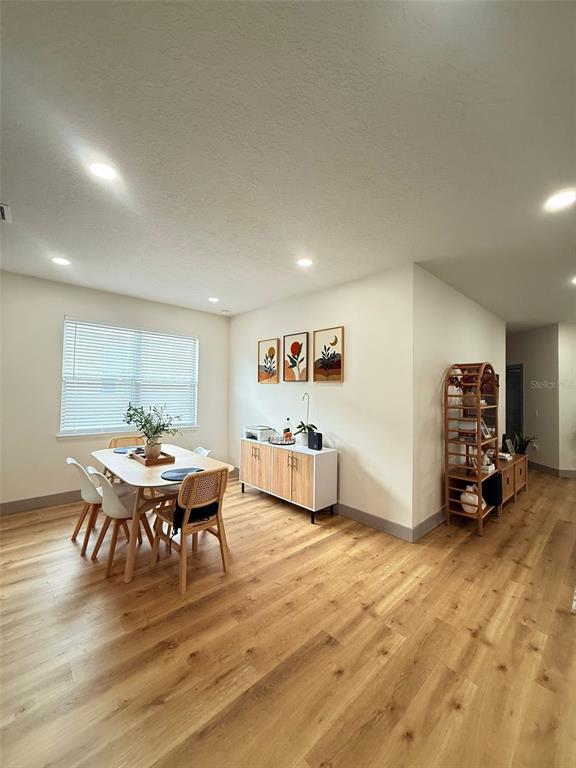 A dining room features light wood flooring, a rectangular table with chairs, and a sideboard — 15020 LAKE AZURE DRIVE, ORLANDO, FL