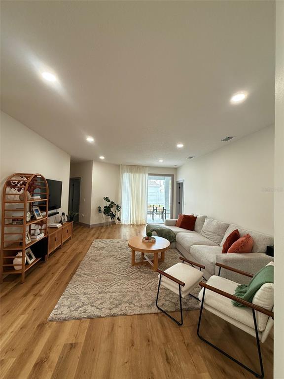A living room features light wood flooring, a sectional sofa, and a wooden shelving unit — 15020 LAKE AZURE DRIVE, ORLANDO, FL