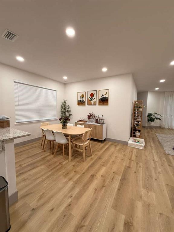 A dining area features a wooden table with four chairs, wall art, and light wood flooring — 15020 LAKE AZURE DRIVE, ORLANDO, FL