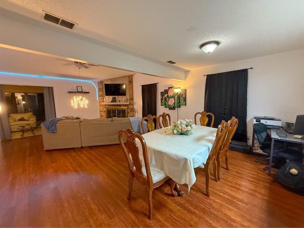A dining area with a wooden table and chairs sits adjacent to a living room — 35058 WHISPERING OAKS BOULEVARD, DADE CITY, FL