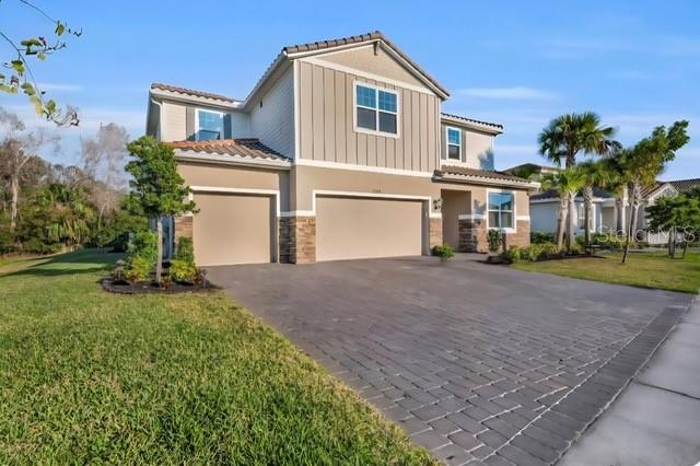A two-story suburban house with a paved driveway and a three-car garage — 7284 GREAT EGRET BOULEVARD, SARASOTA, FL
