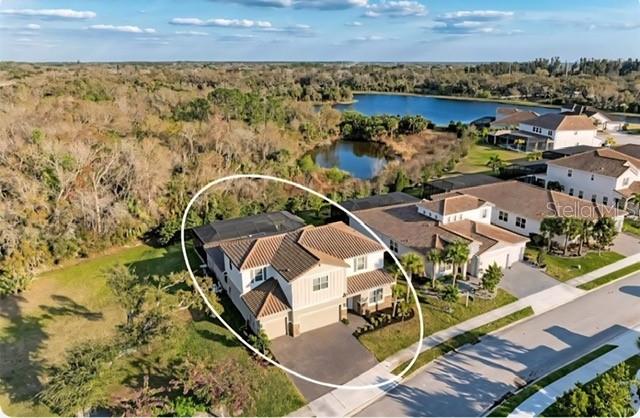 An aerial view shows a two-story suburban house with a tiled roof and screened patio — 7284 GREAT EGRET BOULEVARD, SARASOTA, FL