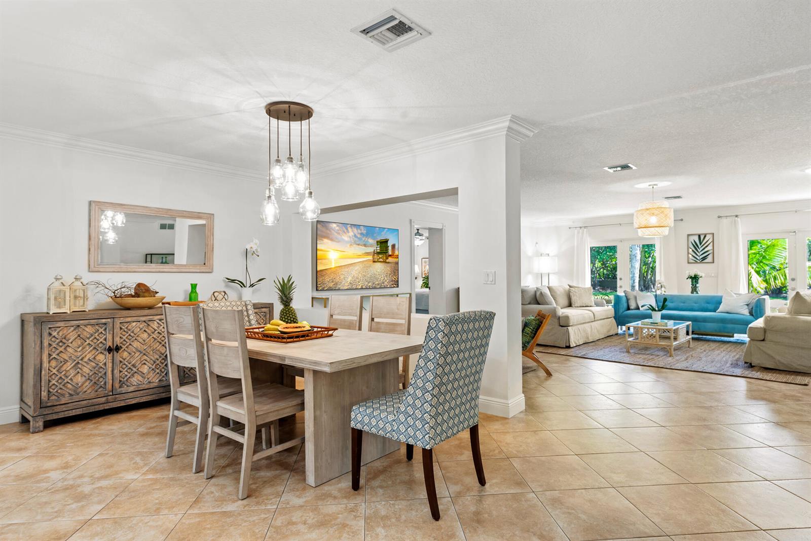 A dining area with a wooden table and patterned chairs opens into a bright living room — 602 N Atlantic Drive, Lantana FL 33460, LANTANA, FL