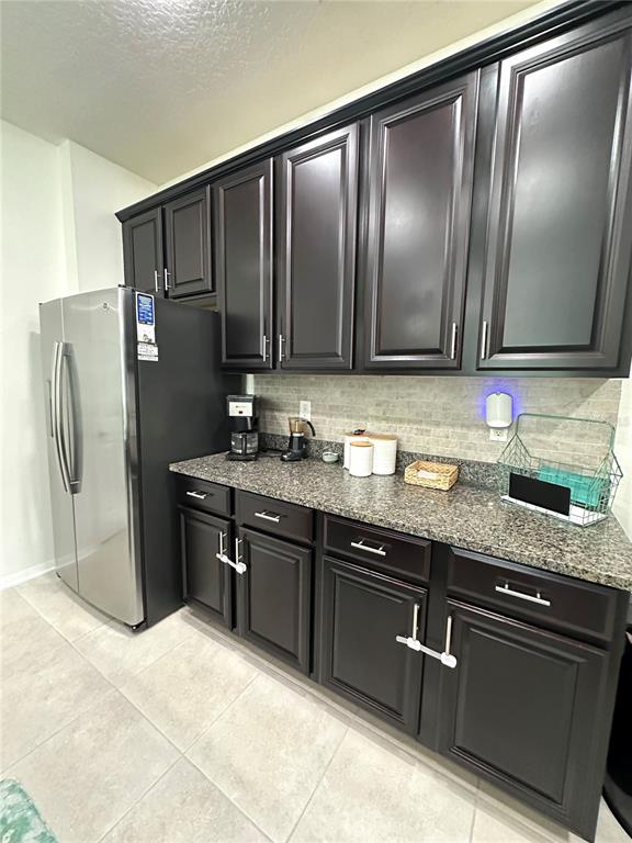 A kitchen features dark wood cabinets, granite countertops, and a stainless steel refrigerator — 4247 ANGELICA LOOP, WESLEY CHAPEL, FL