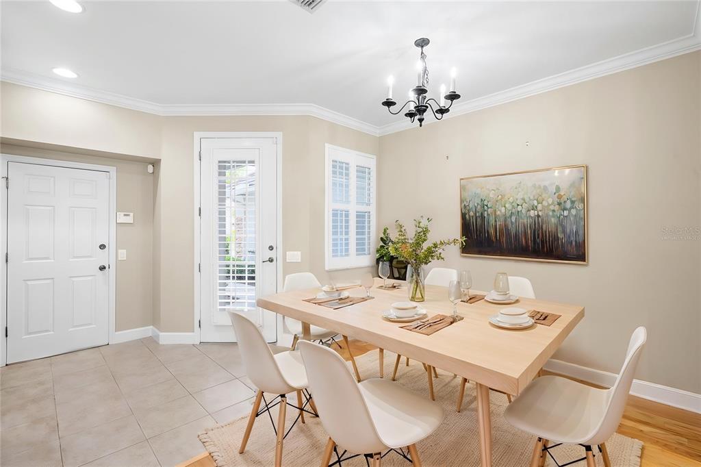A dining room features a light wood table, white chairs, a chandelier, and tile flooring — 14543 MIRABELLE VISTA CIRCLE, TAMPA, FL