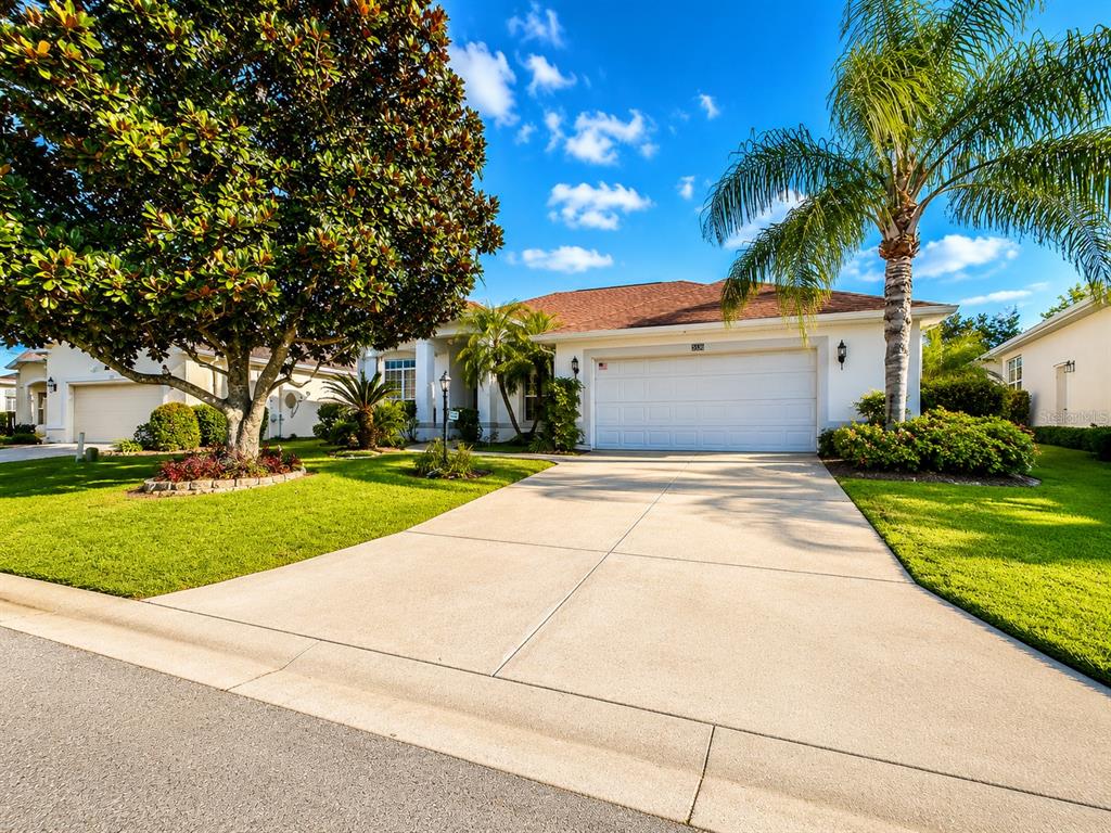 A white single-story house with a two-car garage, a concrete driveway, and a large tree — 5336 TIDEWATER STREET, LEESBURG, FL