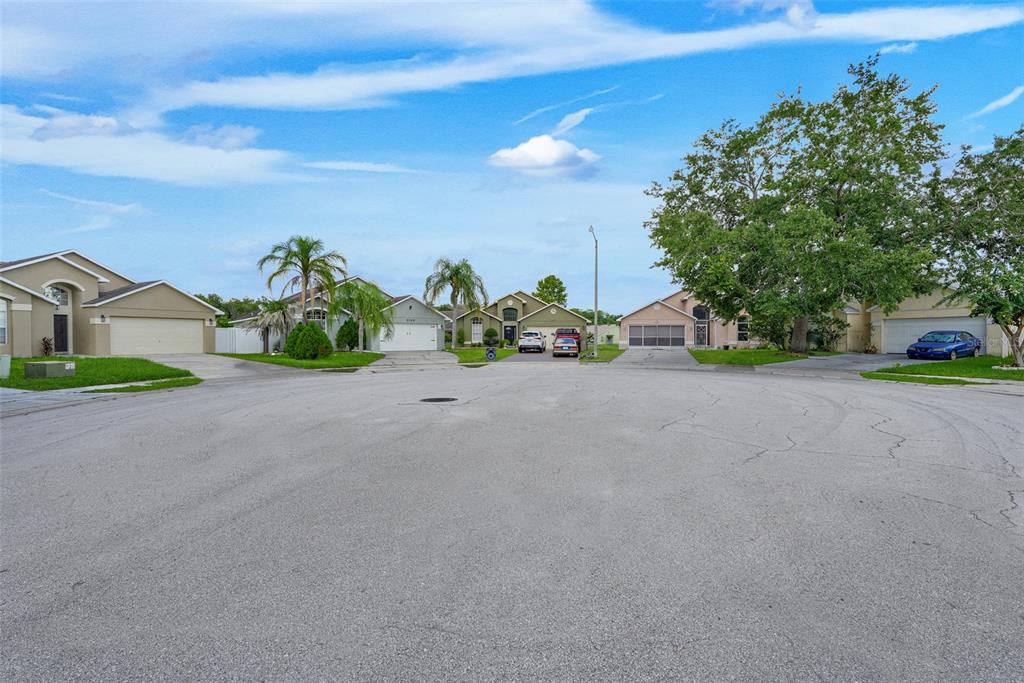 A suburban street view showing several single-family homes with driveways and manicured lawns — 2109 CARBINE COURT, KISSIMMEE, FL