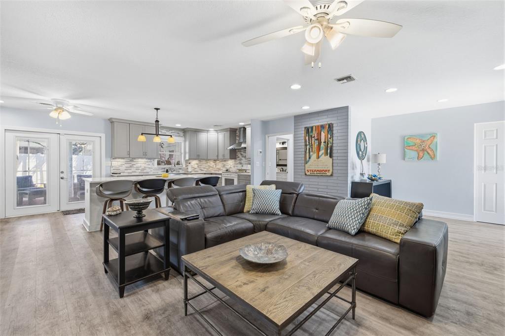 An open-concept living room features a grey sectional sofa, a coffee table, and a kitchen — 4339 50TH AVENUE S, ST PETERSBURG, FL