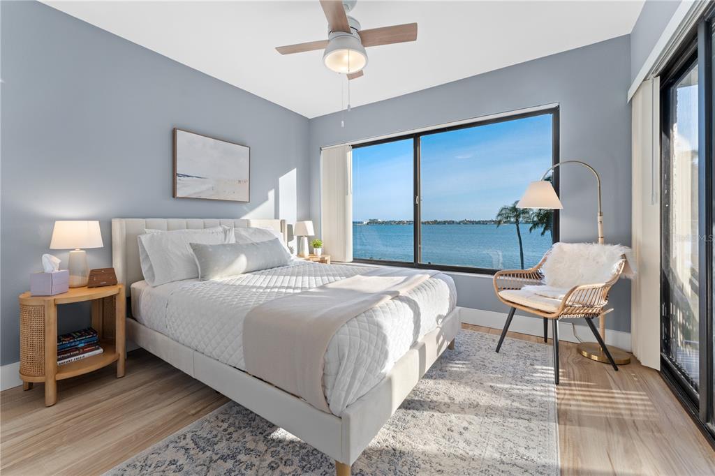 A bedroom with a queen bed, light wood floors, and a large window overlooking the water — 6287 BAHIA DEL MAR CIRCLE UNIT 312, ST PETERSBURG, FL