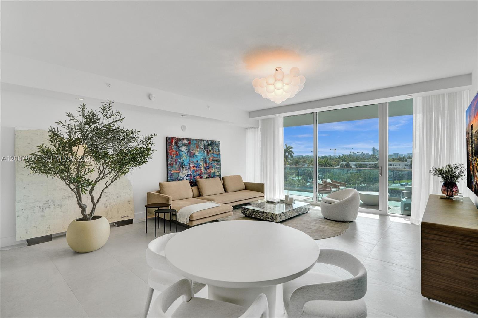 A modern living and dining area features a beige sectional, marble coffee table, and balcony — 10201 Collins Ave # 404, Bal Harbour FL 33154, BAL HARBOUR, FL