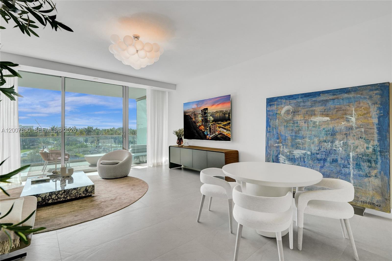 A modern living and dining room features floor-to-ceiling windows, white tile floors, and artwork — 10201 Collins Ave # 404, Bal Harbour FL 33154, BAL HARBOUR, FL