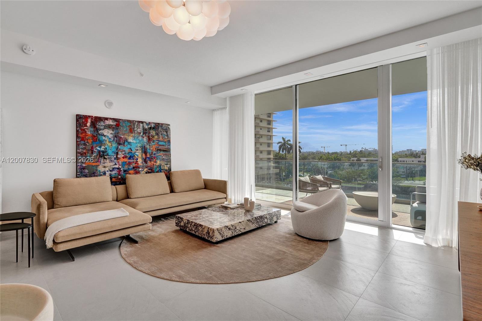 A modern living room features a beige sectional, marble coffee table, and floor-to-ceiling balcony windows — 10201 Collins Ave # 404, Bal Harbour FL 33154, BAL HARBOUR, FL