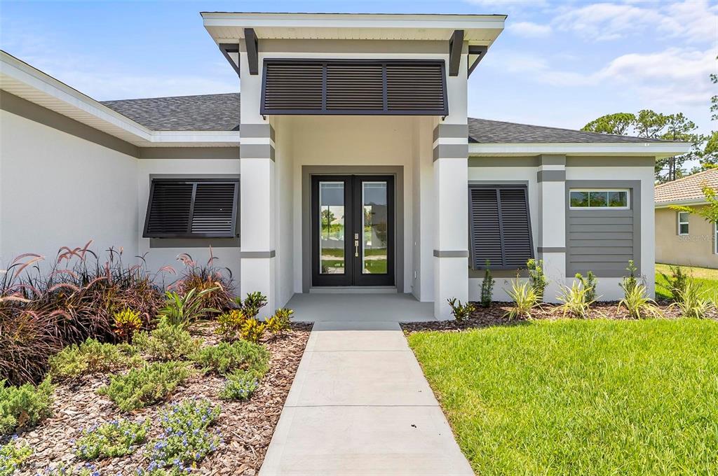 The exterior of a modern house features a concrete walkway leading to a double-door entrance — 1 CLEMENTON LANE, PALM COAST, FL
