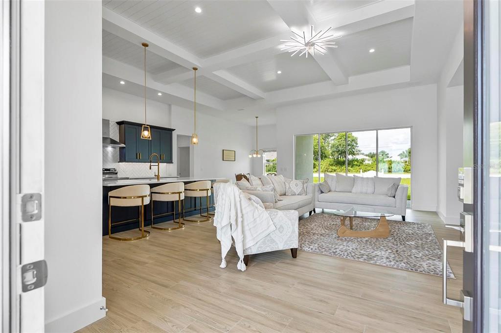 A bright open-concept living room and kitchen with white coffered ceilings and light wood flooring — 1 CLEMENTON LANE, PALM COAST, FL