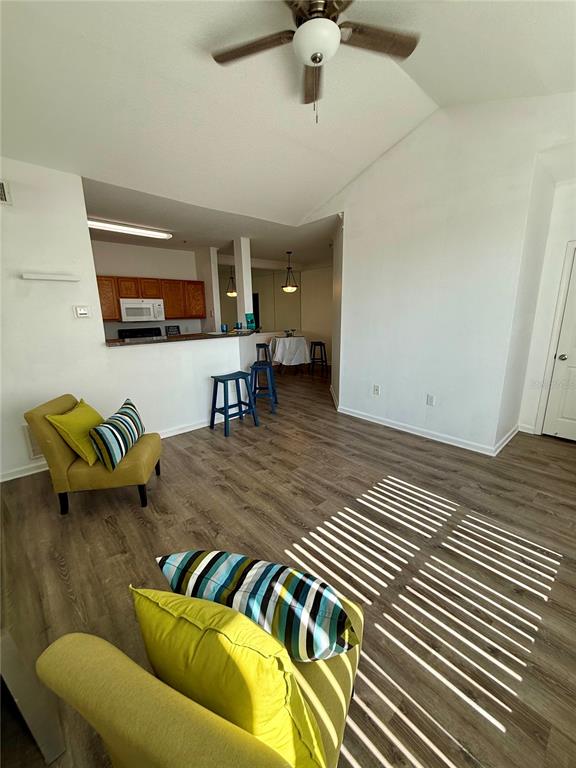 A living room with wood-look flooring, a yellow armchair, and a kitchen breakfast bar — 4802 51ST STREET W UNIT 623, BRADENTON, FL