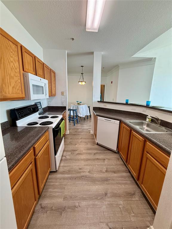 A kitchen features wood cabinets, dark countertops, white appliances, and light wood-look flooring — 4802 51ST STREET W UNIT 623, BRADENTON, FL