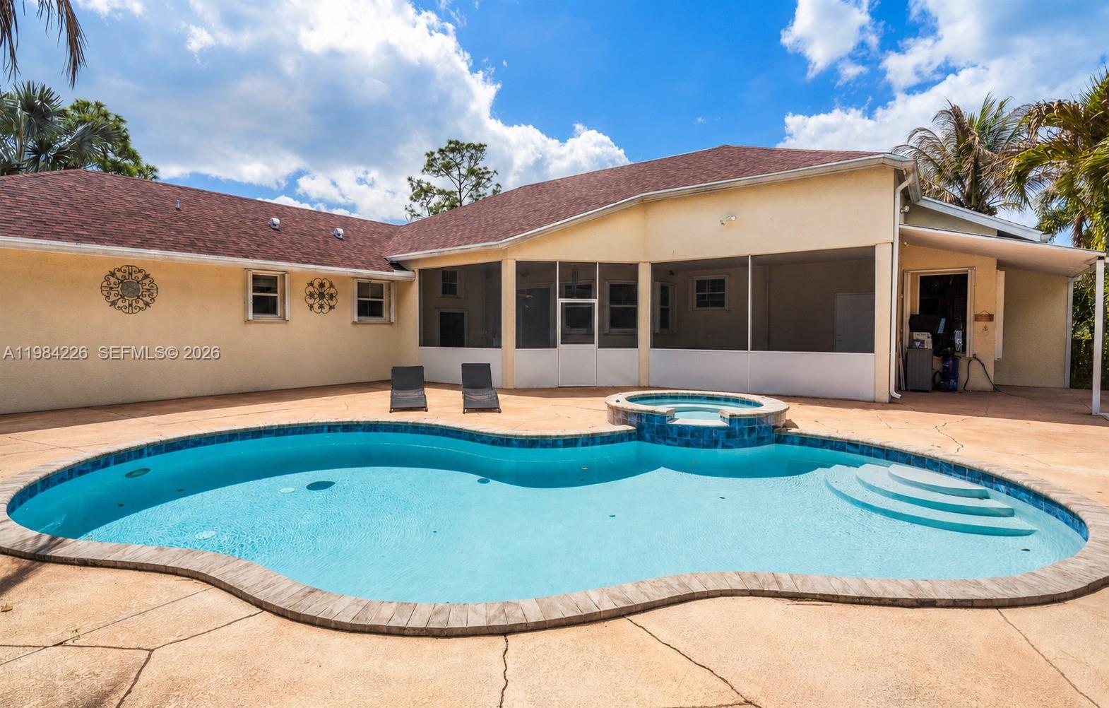 A backyard features a kidney-shaped swimming pool with an attached spa and a screened patio — 5026 Coconut Blvd, Palm Beach FL 33411, PALM BEACH, FL