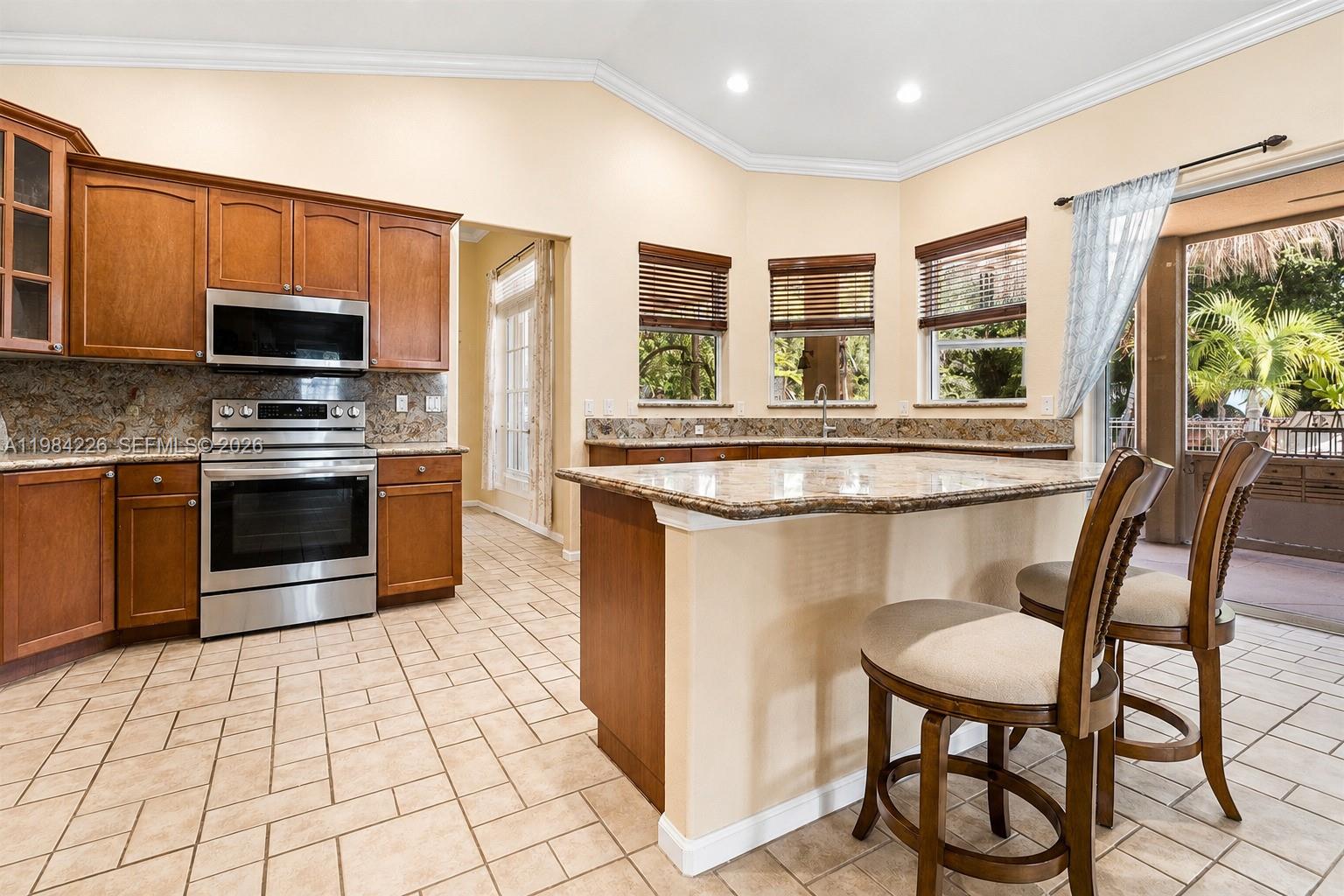 A kitchen features wood cabinets, granite countertops, stainless steel appliances, and a breakfast bar island — 5026 Coconut Blvd, Palm Beach FL 33411, PALM BEACH, FL