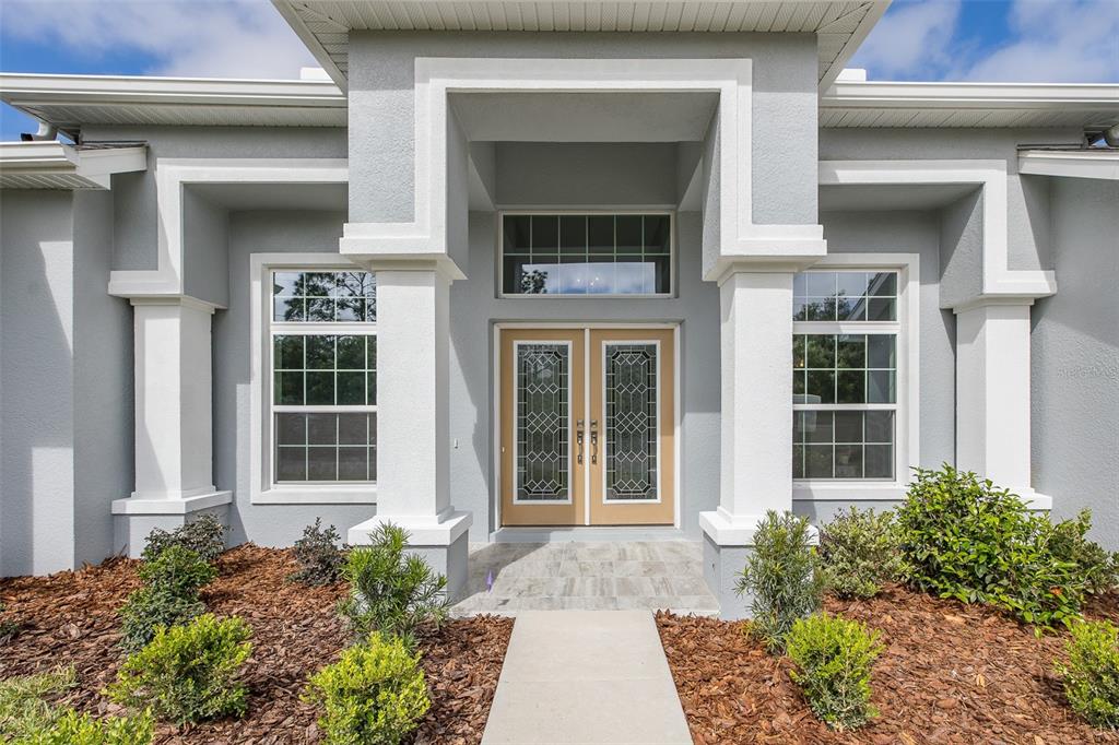 A gray house exterior features a covered entryway with double doors and white columns — 38 VINCA STREET, HOMOSASSA, FL