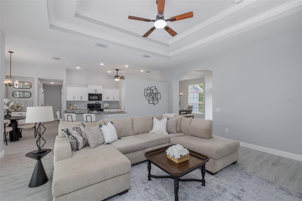 A living room with a sectional sofa, coffee table, and open kitchen in the background — 38 VINCA STREET, HOMOSASSA, FL