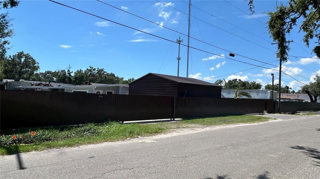 A brown metal fence encloses a property with a shed and a mobile home — 2001 S 51ST STREET, TAMPA, FL