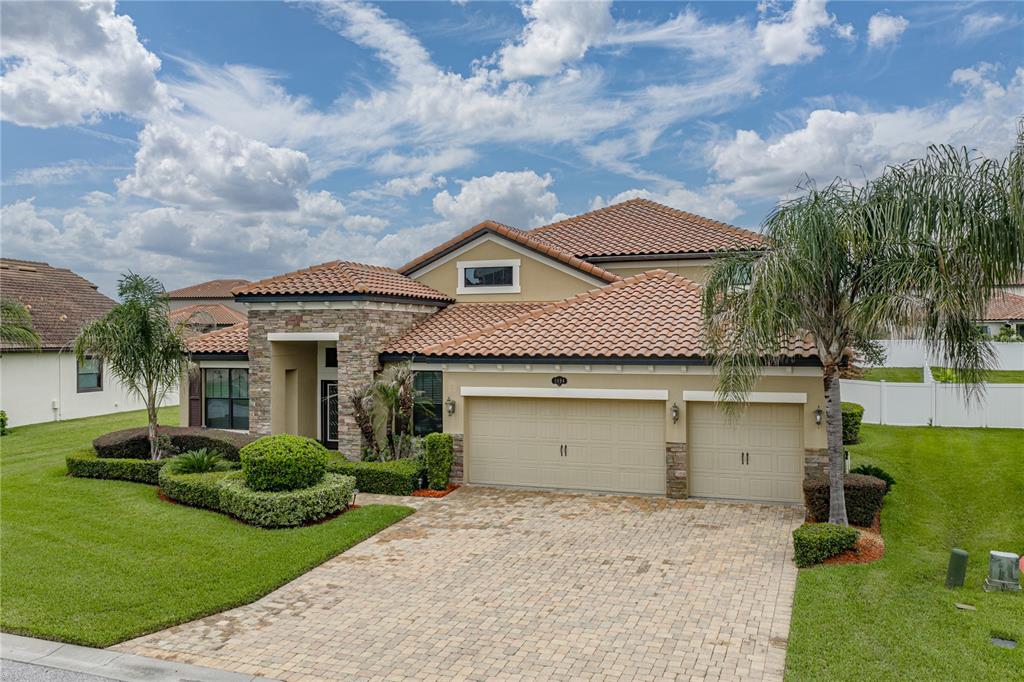 A single-story house with a tile roof, stone facade, and a two-car garage — 1894 VIA LAGO DRIVE, LAKELAND, FL